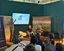 Steffen Volk, Projektleiter des CEV SH auf dem Waterkant Festival. (links) Publikum bei der Waterkant-Konferenz in Kiel, blickt zur Bühne mit Rollups und Bildschirm mit Karte. Ein Referent zeigt auf die Karte, zwei weitere sitzen auf der Bühne.